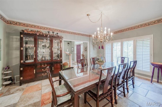 dining area with a chandelier, stone tile floors, crown molding, and baseboards
