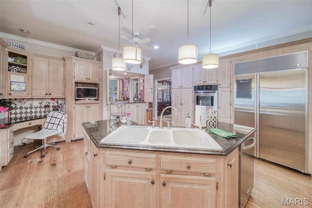 kitchen featuring stainless steel appliances, a sink, a center island with sink, ornamental molding, and light wood-style floors
