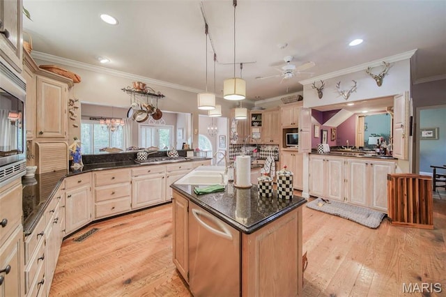 kitchen featuring a peninsula, crown molding, a kitchen island with sink, ceiling fan, and a sink