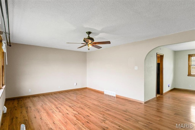 1219 N Park St, Hardin, IL 62047 - empty room with a ceiling fan, arched walkways, light wood finished floors, baseboards, and a textured ceiling