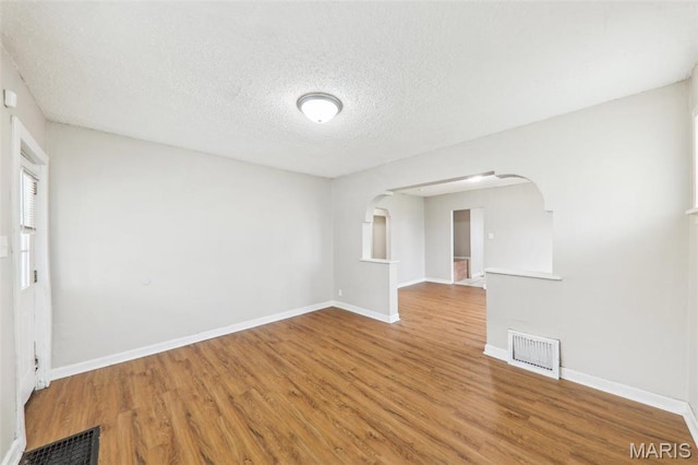 241 Dammert Ave, Saint Louis, MO 63125 - empty room with wood finished floors, a textured ceiling, baseboards, and arched walkways