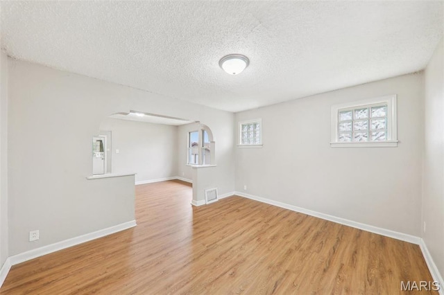 241 Dammert Ave, Saint Louis, MO 63125 - basement with light wood-type flooring, a textured ceiling, baseboards, and arched walkways