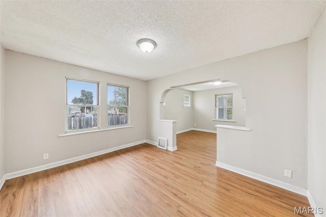 241 Dammert Ave, Saint Louis, MO 63125 - unfurnished room with arched walkways, wood finished floors, plenty of natural light, and a textured ceiling