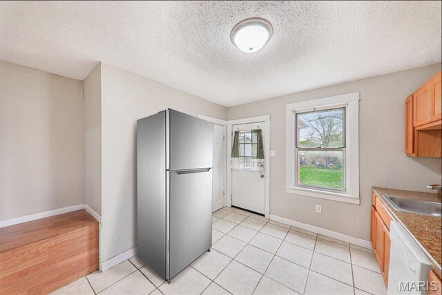 241 Dammert Ave, Saint Louis, MO 63125 - kitchen with freestanding refrigerator, white dishwasher, a sink, a textured ceiling, and baseboards