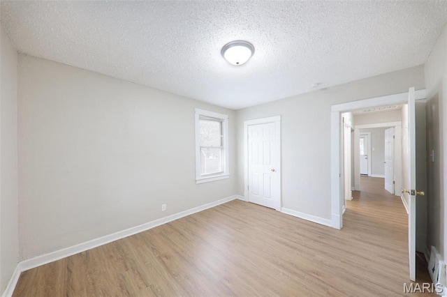 241 Dammert Ave, Saint Louis, MO 63125 - unfurnished bedroom with light wood-style floors, baseboards, a textured ceiling, and a closet