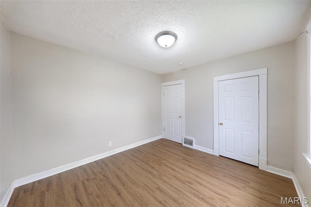 241 Dammert Ave, Saint Louis, MO 63125 - unfurnished bedroom with wood finished floors, baseboards, and a textured ceiling