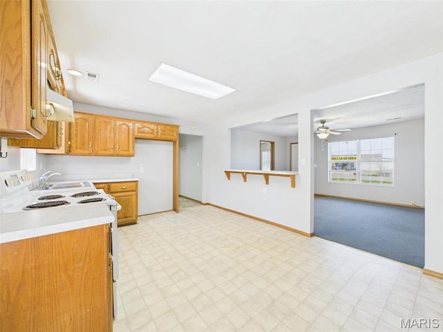 710 W Jefferson Ave, Conway, MO 65632 - kitchen with white electric stove, light countertops, a sink, light floors, and brown cabinets