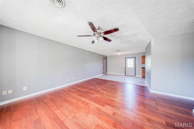 unfurnished living room with wood finished floors, a ceiling fan, a textured ceiling, and baseboards