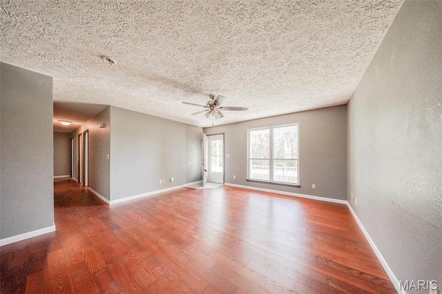 spare room with wood finished floors, ceiling fan, baseboards, and a textured ceiling