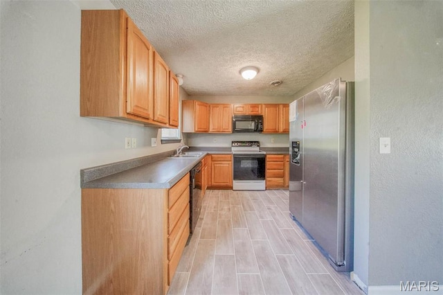 kitchen featuring black appliances, a textured ceiling, a sink, and baseboards