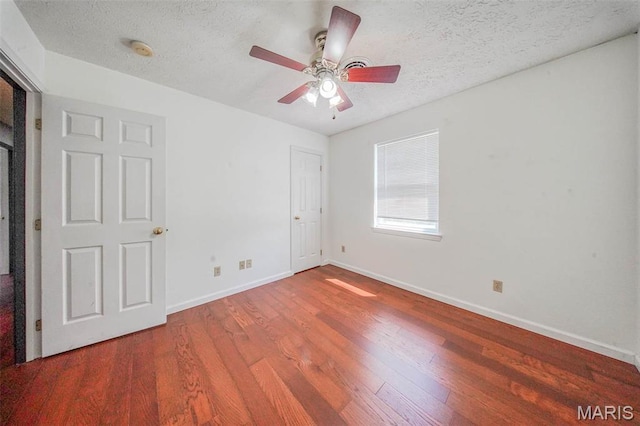 unfurnished bedroom with wood finished floors, a textured ceiling, baseboards, and a ceiling fan