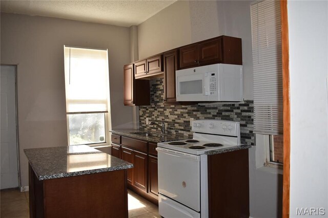 2912 Indiana Ave, Saint Louis, MO 63118 - kitchen featuring white appliances, a sink, tasteful backsplash, dark stone countertops, and light tile patterned floors