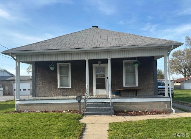 view of front of house featuring covered porch, a shingled roof, and a front lawn