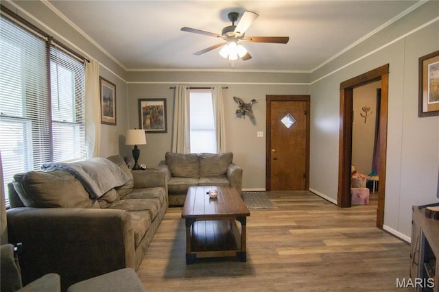 living room with wood finished floors, a ceiling fan, crown molding, and baseboards