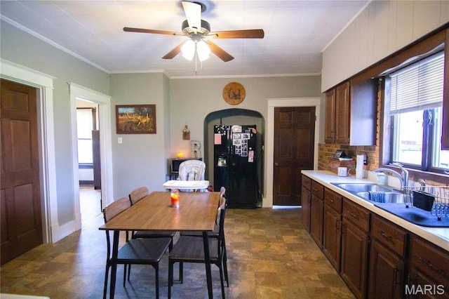 kitchen featuring ornamental molding, a ceiling fan, light countertops, black fridge with ice dispenser, and a sink