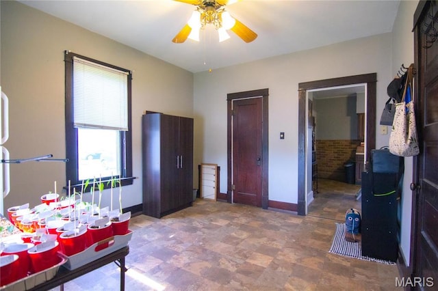 bedroom featuring baseboards, a ceiling fan, and stone finish floors