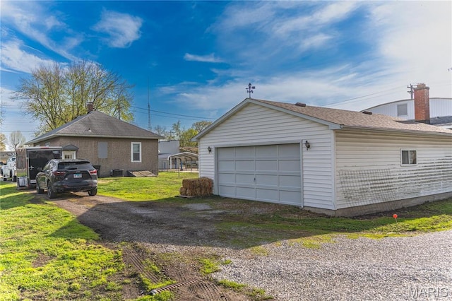 view of property exterior with dirt driveway, an outdoor structure, a garage, and a lawn