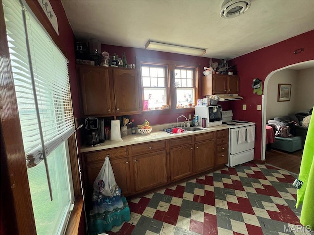 1714 Price St, Hannibal, MO 63401 - kitchen with electric range, a sink, under cabinet range hood, arched walkways, and light countertops