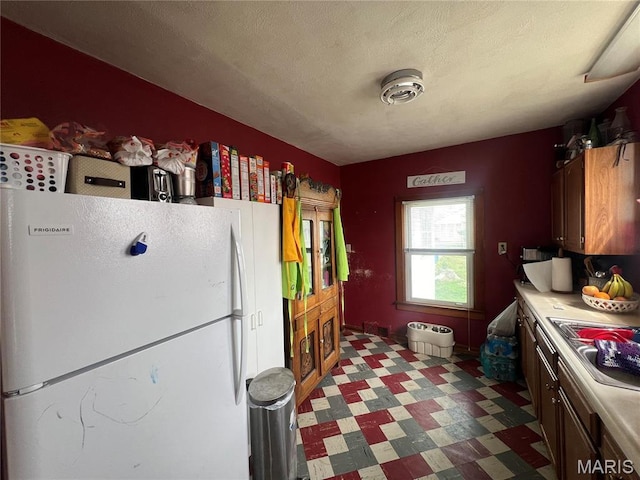 1714 Price St, Hannibal, MO 63401 - kitchen featuring freestanding refrigerator, tile patterned floors, light countertops, a sink, and a textured ceiling