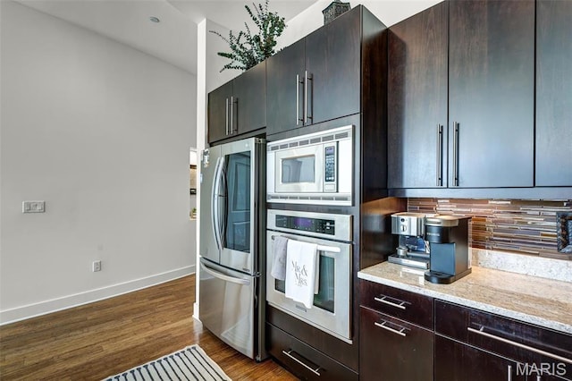 8025 Maryland Ave Unit 2H, Saint Louis, MO 63105 - kitchen featuring stainless steel appliances, baseboards, decorative backsplash, dark wood finished floors, and light stone counters
