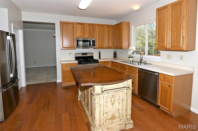 kitchen featuring stainless steel appliances, a sink, dark wood-style flooring, and a kitchen island