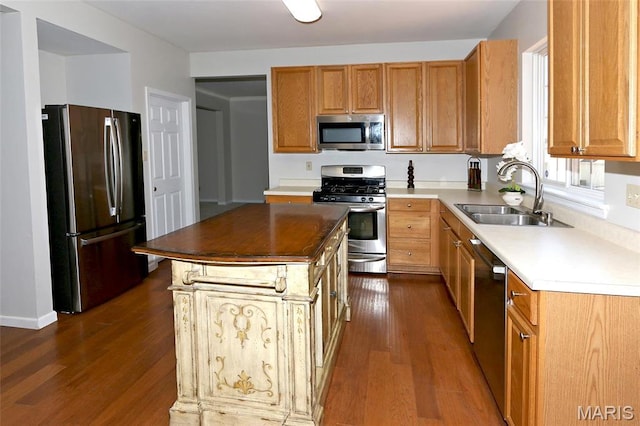 kitchen with appliances with stainless steel finishes, a sink, dark wood finished floors, and a center island