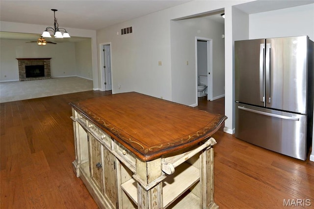 kitchen with freestanding refrigerator, dark wood-type flooring, a chandelier, pendant lighting, and a brick fireplace