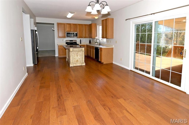 kitchen with appliances with stainless steel finishes, a sink, a chandelier, dark wood-style flooring, and baseboards