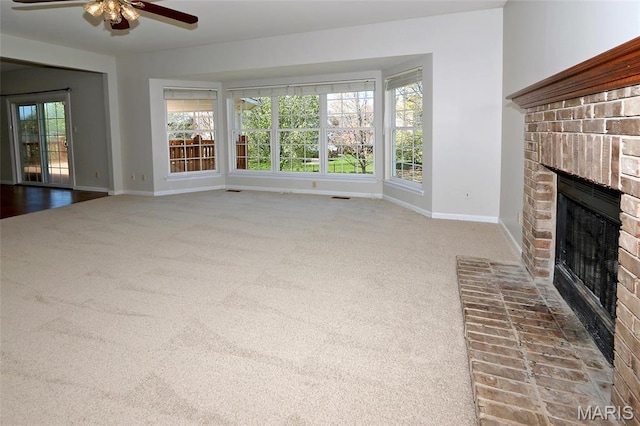 unfurnished living room with a brick fireplace, carpet, a ceiling fan, and baseboards