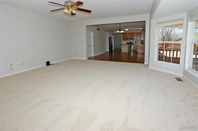 unfurnished living room with carpet flooring, a chandelier, baseboards, and a ceiling fan