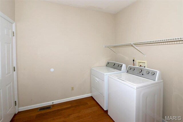 laundry room with washing machine and clothes dryer, wood finished floors, and baseboards