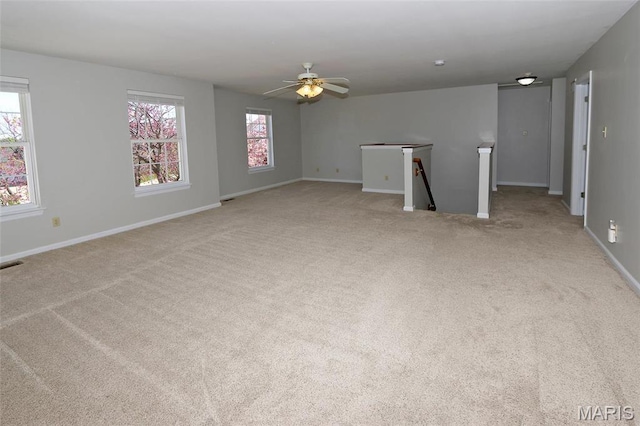 carpeted spare room featuring a ceiling fan and baseboards