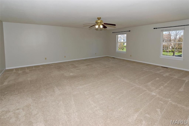 spare room with baseboards, light colored carpet, and a ceiling fan