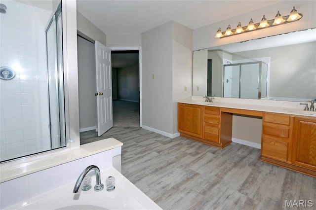 bathroom with a stall shower, wood finished floors, and double vanity