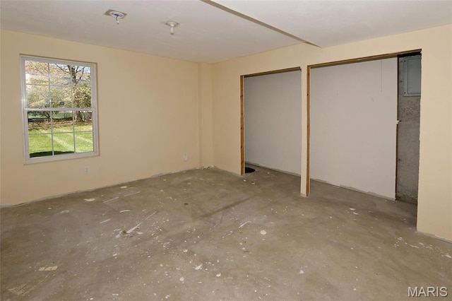 unfurnished bedroom with two closets and unfinished concrete flooring