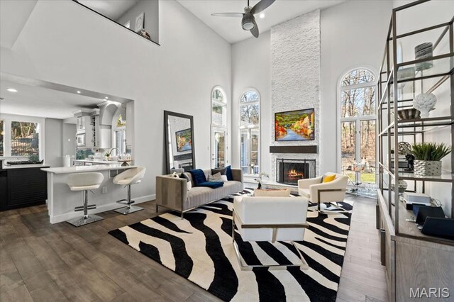 1909 Shepard Rd, Wildwood, MO 63038 - living room with a towering ceiling, dark wood-style flooring, a ceiling fan, a stone fireplace, and baseboards