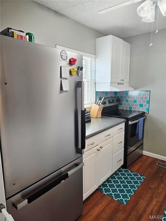 10340 Corbeil Dr, Saint Louis, MO 63146 - kitchen with stainless steel appliances, dark wood-style flooring, white cabinetry, ceiling fan, and decorative backsplash
