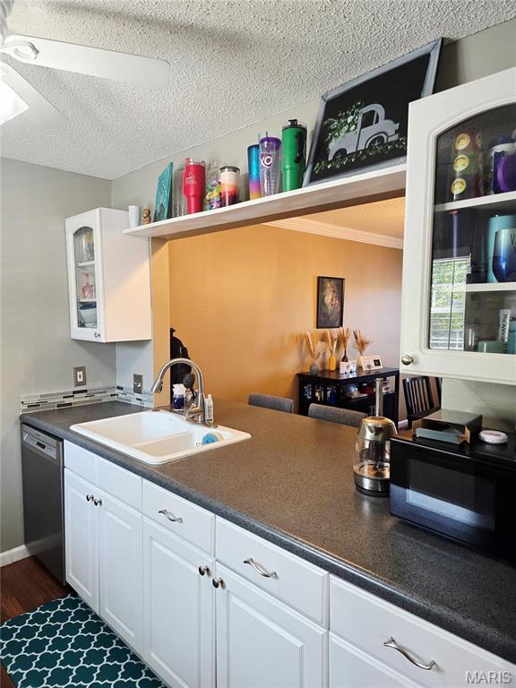 10340 Corbeil Dr, Saint Louis, MO 63146 - kitchen with stainless steel dishwasher, a sink, white cabinets, a textured ceiling, and black microwave