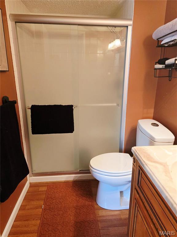 10340 Corbeil Dr, Saint Louis, MO 63146 - full bath with wood finished floors, toilet, a shower stall, vanity, and a textured ceiling