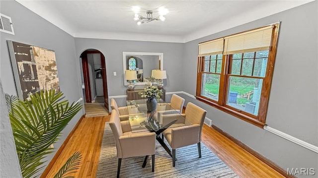 4411 Nelson Dr, Saint Louis, MO 63121 - dining room featuring arched walkways, wood finished floors, a chandelier, and baseboards