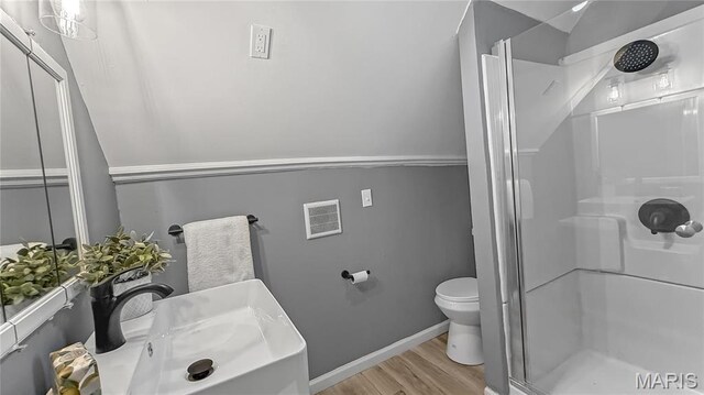 4411 Nelson Dr, Saint Louis, MO 63121 - bathroom featuring wood finished floors, a shower stall, toilet, baseboards, and vanity
