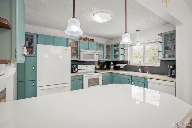 kitchen with white appliances, a sink, a textured ceiling, light countertops, and hanging light fixtures
