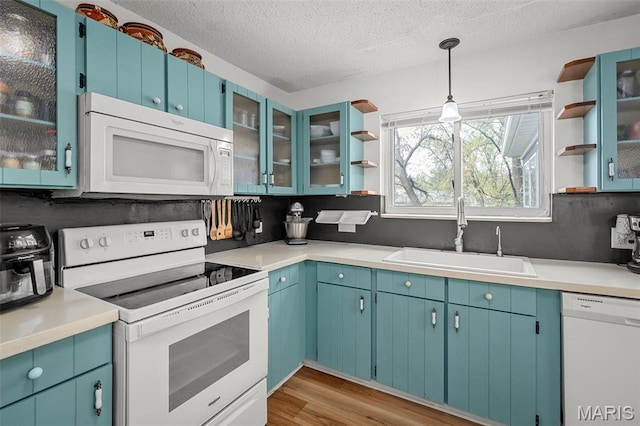 kitchen with white appliances, a sink, open shelves, light wood-style floors, and a textured ceiling