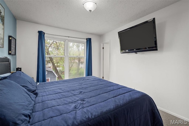 bedroom with a textured ceiling, carpet floors, and baseboards
