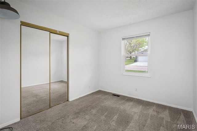 unfurnished bedroom featuring carpet, a closet, baseboards, and a textured ceiling