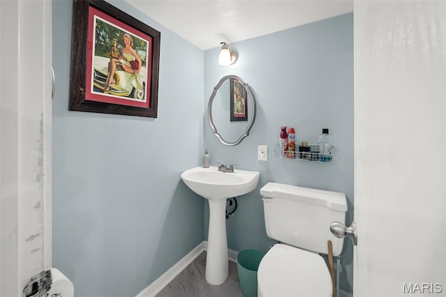 bathroom with marble look tiles, toilet, and baseboards