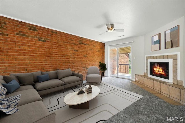 carpeted living area featuring brick wall, a fireplace, and a ceiling fan