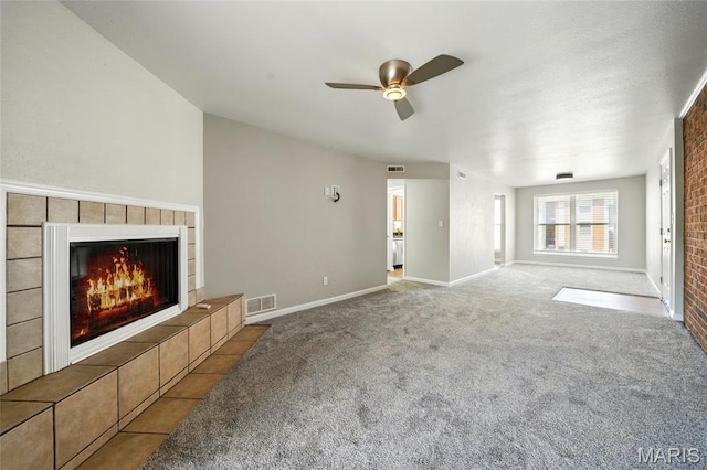 unfurnished living room featuring a tile fireplace, carpet, a ceiling fan, and baseboards