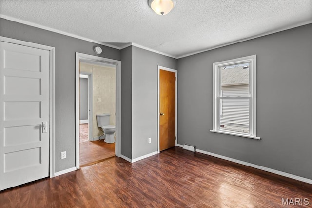120 E 1st St, Hartford, IL 62048 - unfurnished bedroom featuring a textured ceiling, dark wood-type flooring, baseboards, ornamental molding, and connected bathroom