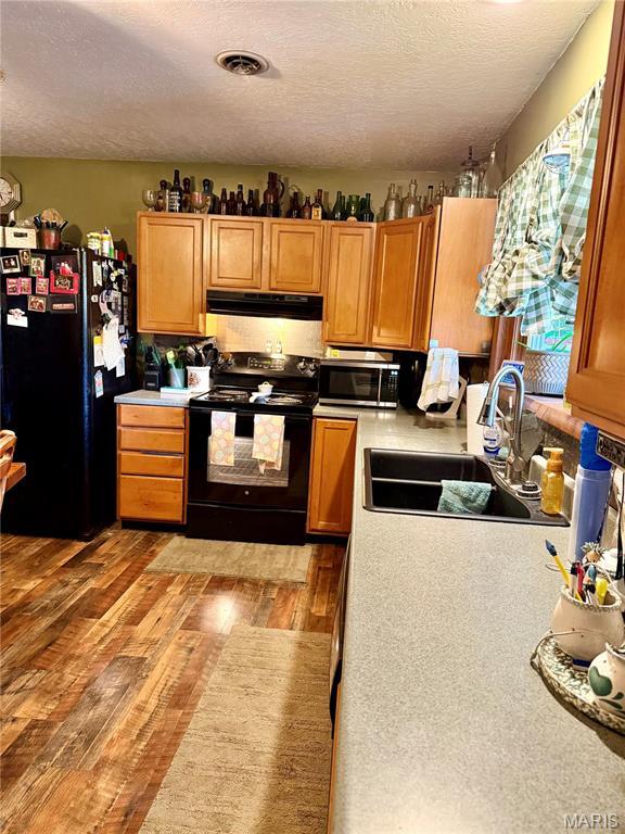 42 Berger Rd, Middletown, MO 63359 - kitchen with black appliances, a sink, a textured ceiling, light wood finished floors, and light countertops